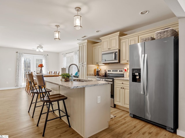 kitchen with decorative light fixtures, light stone counters, appliances with stainless steel finishes, and cream cabinets