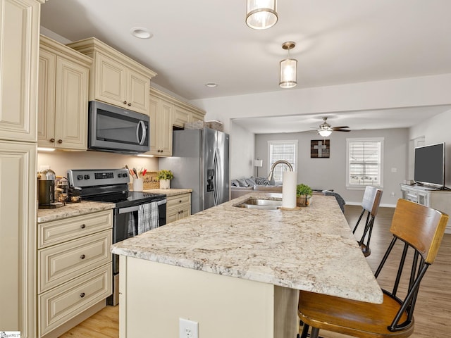 kitchen featuring pendant lighting, sink, an island with sink, appliances with stainless steel finishes, and a kitchen bar