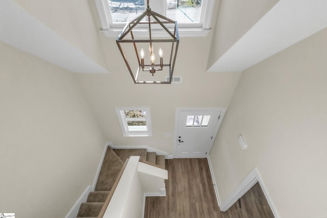 foyer featuring dark wood-type flooring, a towering ceiling, and a chandelier