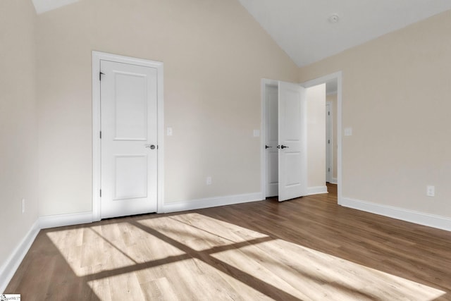 unfurnished bedroom with wood-type flooring and high vaulted ceiling