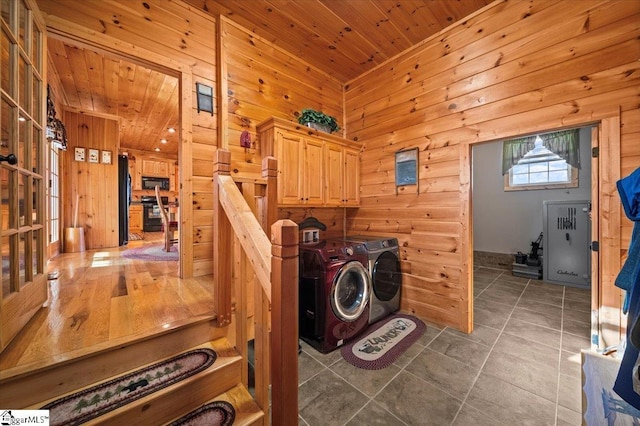 washroom featuring wood walls, washer and clothes dryer, cabinets, and wood ceiling