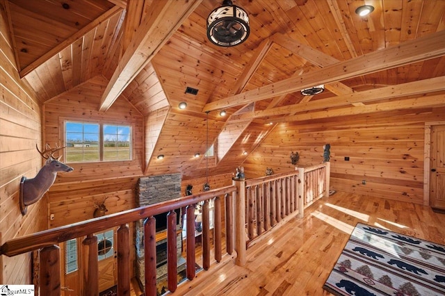 corridor featuring lofted ceiling with beams, light wood-type flooring, wood ceiling, and wooden walls