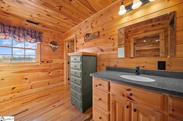 bathroom featuring hardwood / wood-style floors, vanity, wood walls, and wooden ceiling