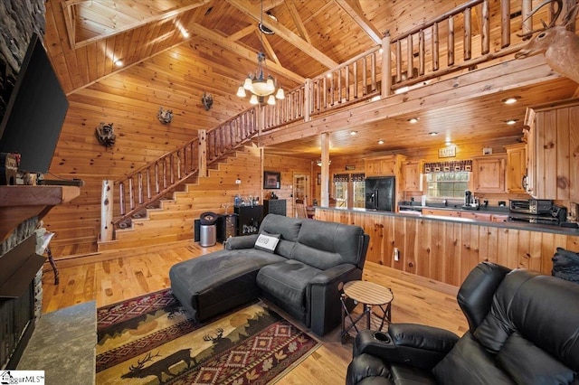 living room with light wood-type flooring, wooden walls, high vaulted ceiling, wooden ceiling, and a chandelier