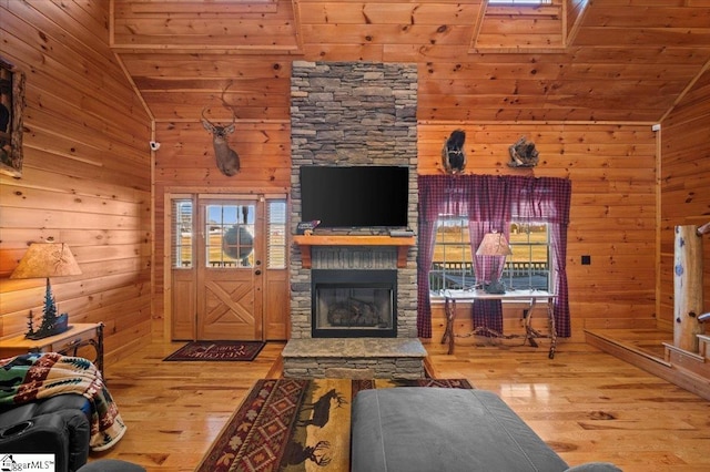 living room with a stone fireplace, light wood-type flooring, wooden walls, and wooden ceiling