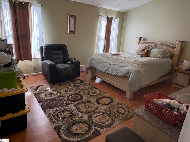 bedroom with multiple windows and hardwood / wood-style flooring