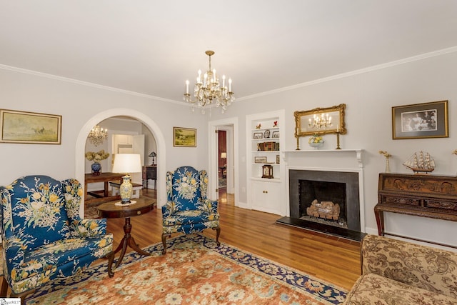 living room featuring hardwood / wood-style floors, an inviting chandelier, built in features, and ornamental molding