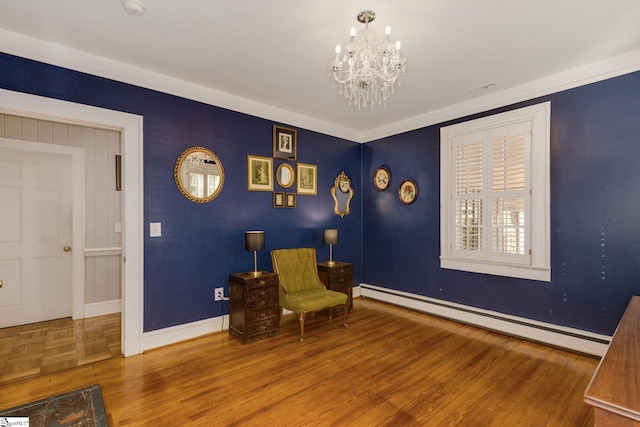 living area with hardwood / wood-style flooring, a notable chandelier, ornamental molding, and baseboard heating