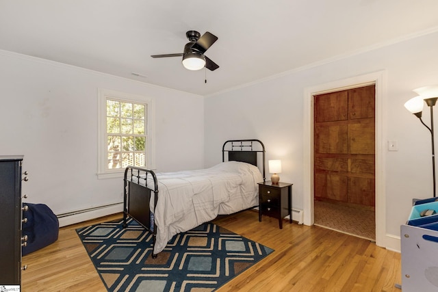 bedroom featuring ceiling fan, ornamental molding, light wood-type flooring, and a baseboard heating unit