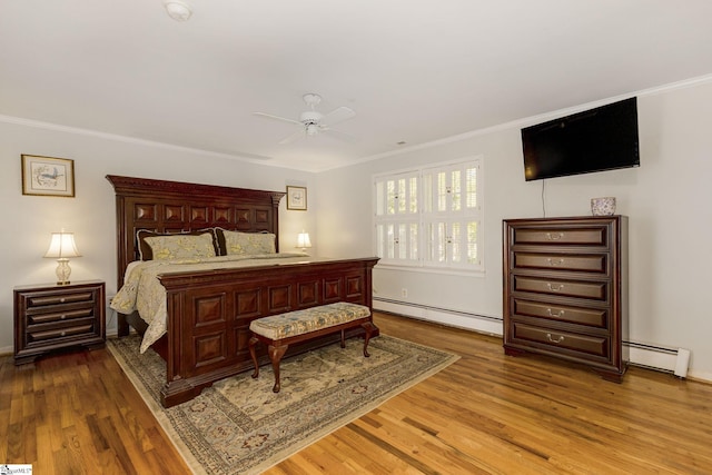 bedroom featuring hardwood / wood-style flooring, ceiling fan, crown molding, and a baseboard heating unit