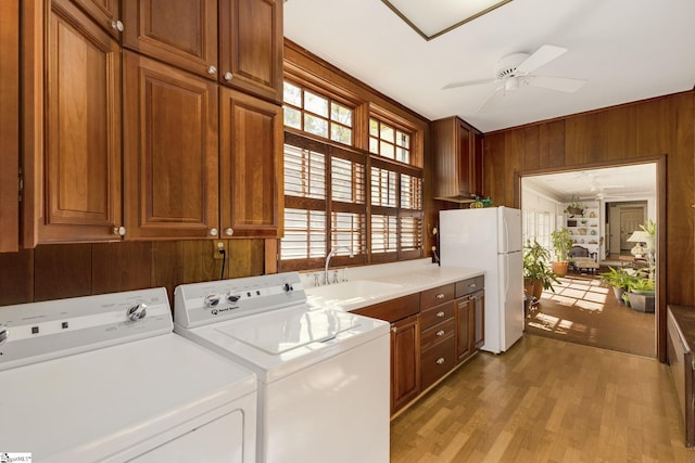 washroom featuring ceiling fan, sink, cabinets, light hardwood / wood-style floors, and washer and clothes dryer