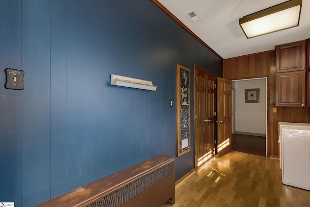 hallway with dark hardwood / wood-style floors, wood walls, and washer / dryer