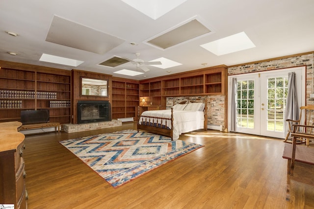 bedroom with access to exterior, french doors, a large fireplace, a baseboard radiator, and hardwood / wood-style floors