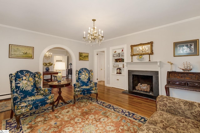 living room with built in shelves, a notable chandelier, ornamental molding, and hardwood / wood-style floors