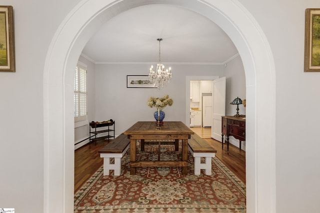 dining area featuring a chandelier, ornamental molding, a baseboard heating unit, and hardwood / wood-style flooring