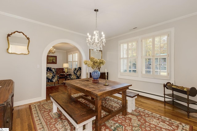 dining room featuring hardwood / wood-style floors, ornamental molding, and a notable chandelier