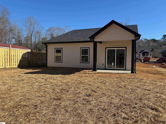 rear view of property with fence and a lawn