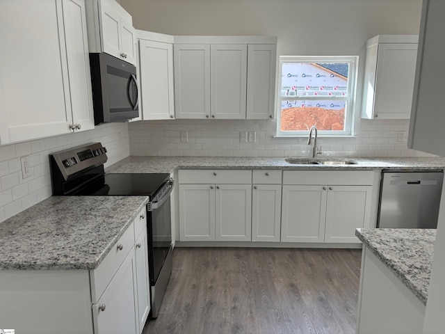 kitchen with light wood-style flooring, appliances with stainless steel finishes, white cabinets, and a sink