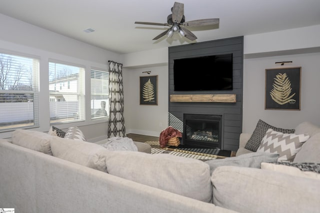 living room featuring hardwood / wood-style flooring, ceiling fan, and a fireplace