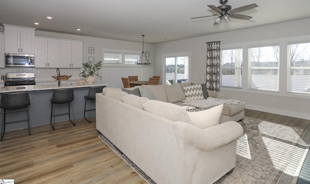 living room with light hardwood / wood-style flooring, ceiling fan, and sink