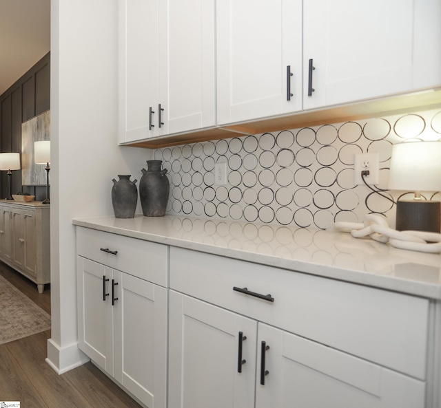 kitchen featuring tasteful backsplash, light stone countertops, dark hardwood / wood-style flooring, and white cabinets