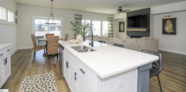 kitchen featuring pendant lighting, white cabinets, sink, and an island with sink