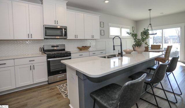 kitchen featuring pendant lighting, sink, stainless steel appliances, and a kitchen island with sink