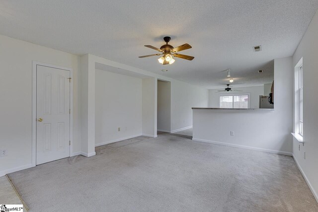 spare room with light carpet, a textured ceiling, and ceiling fan