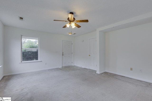 unfurnished room with light carpet, ceiling fan, and a textured ceiling