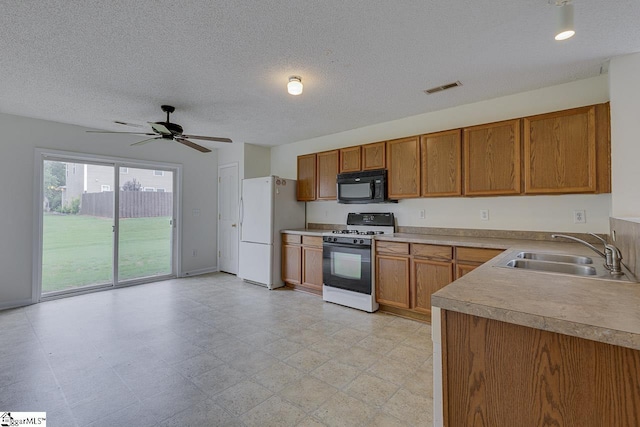 kitchen featuring a textured ceiling, white appliances, ceiling fan, and sink