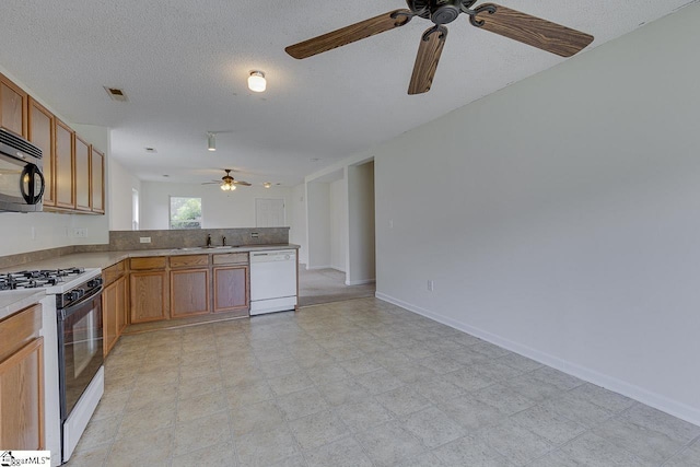 kitchen featuring kitchen peninsula, a textured ceiling, white appliances, ceiling fan, and sink