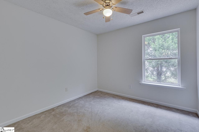 spare room featuring ceiling fan, light colored carpet, and a textured ceiling