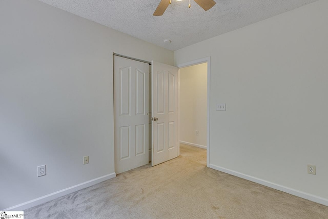 unfurnished bedroom with a textured ceiling, light colored carpet, and ceiling fan