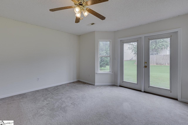 empty room with french doors, a textured ceiling, light colored carpet, and ceiling fan