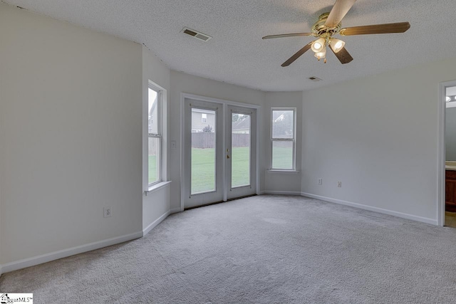 unfurnished room with ceiling fan, light colored carpet, and a textured ceiling