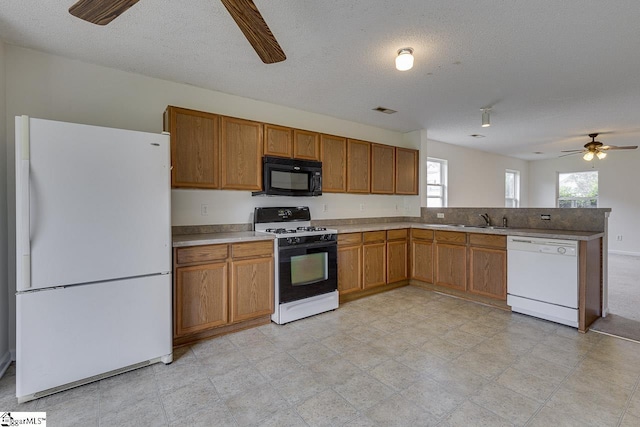 kitchen with a textured ceiling, white appliances, ceiling fan, and sink