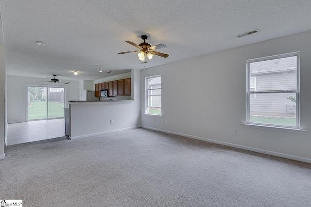 unfurnished living room featuring light carpet and ceiling fan