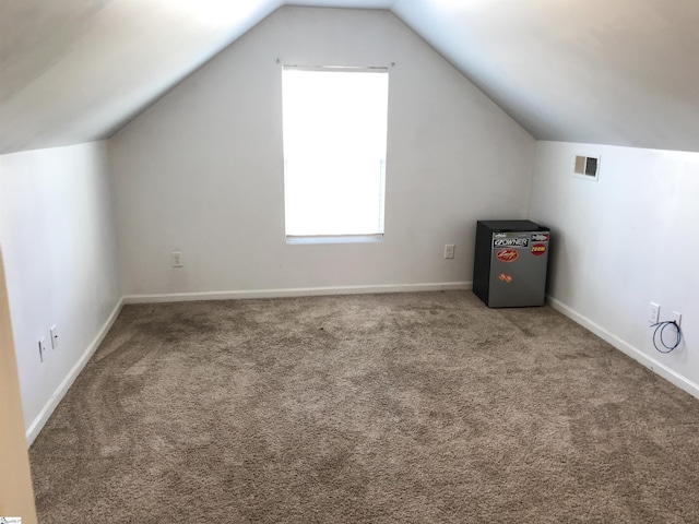 bonus room with carpet flooring and vaulted ceiling