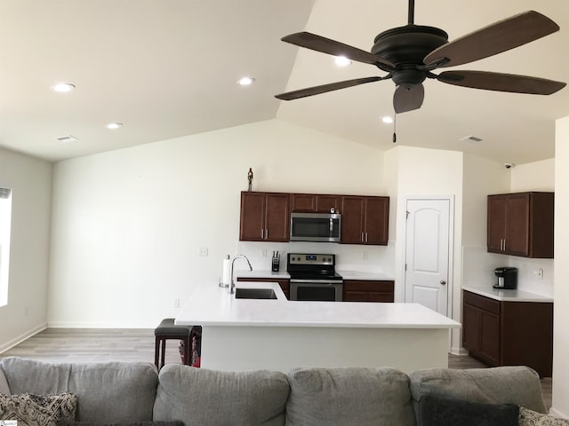 kitchen with appliances with stainless steel finishes, vaulted ceiling, ceiling fan, sink, and light hardwood / wood-style floors