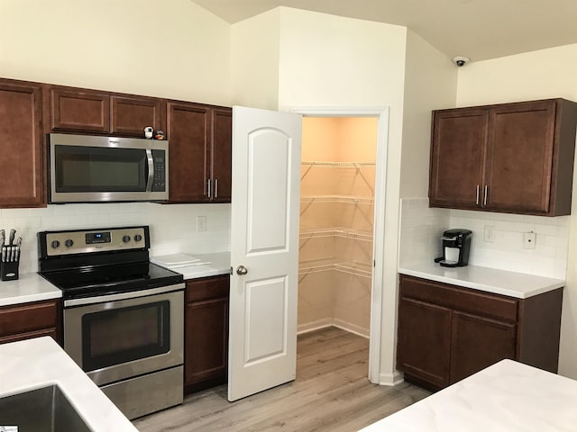 kitchen featuring dark brown cabinets, light hardwood / wood-style floors, backsplash, and appliances with stainless steel finishes