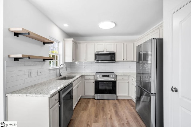 kitchen featuring appliances with stainless steel finishes, tasteful backsplash, white cabinetry, and sink