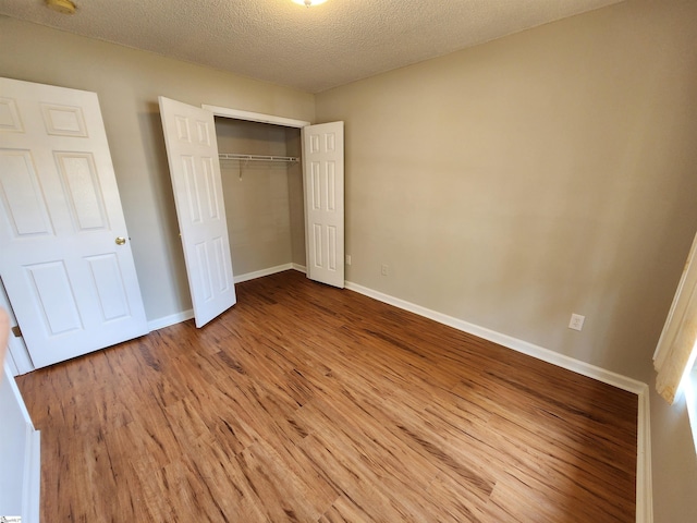 unfurnished bedroom featuring wood-type flooring, a textured ceiling, and a closet