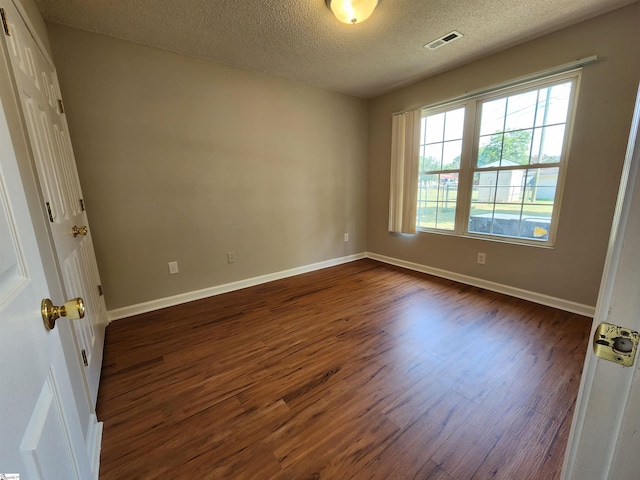 unfurnished room with a textured ceiling and dark wood-type flooring