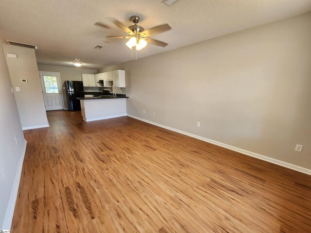 unfurnished living room featuring a textured ceiling, light hardwood / wood-style floors, and ceiling fan