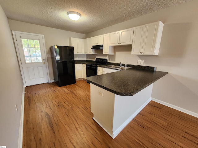 kitchen with kitchen peninsula, white cabinetry, sink, and black appliances