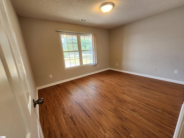 spare room featuring a textured ceiling and dark wood-type flooring