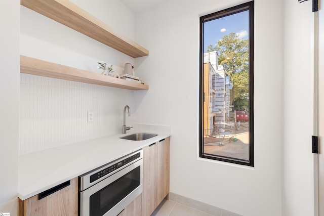 kitchen featuring light tile patterned flooring, light brown cabinetry, and sink