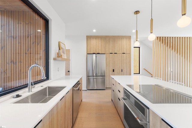 kitchen featuring stainless steel appliances, sink, pendant lighting, light brown cabinets, and light hardwood / wood-style floors