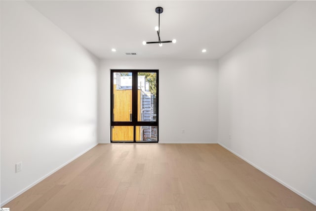 empty room with a chandelier and light wood-type flooring