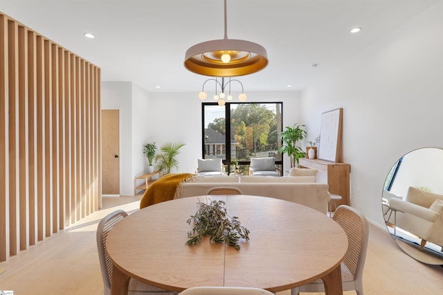 dining area with light wood-type flooring and an inviting chandelier